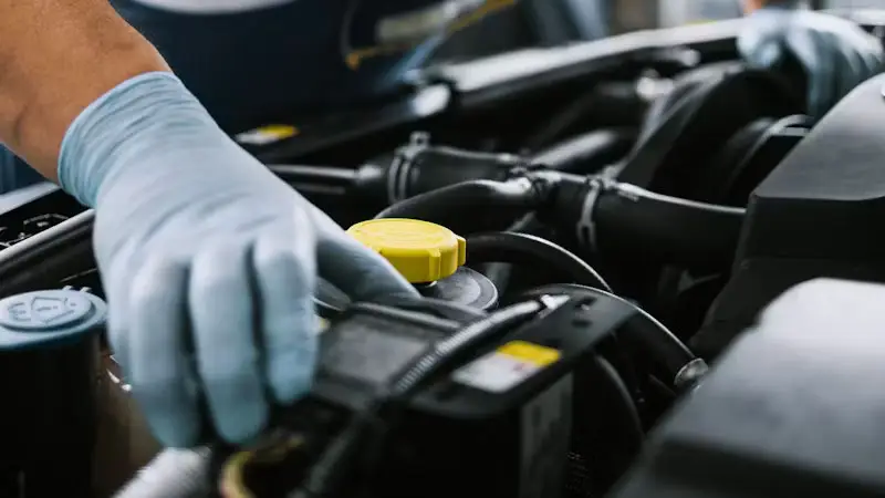 Entretien du compartiment moteur par une main gantée